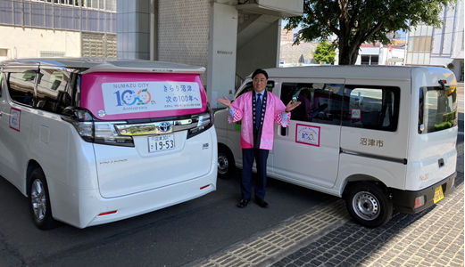 市長が100周年PR用マグネットシートを貼り付けた公用車を紹介している様子