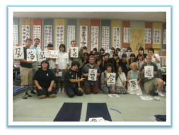 武道・文化体験で書道を体験するカラマズー市民。漢字を書いた半紙を持ち記念撮影。