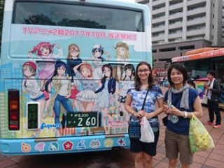 アニメが描かれたバスの後ろに二人が並んだ写真